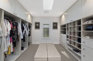 Blog - Velux skylight above a luxury walk-in wardrobe with built-in shelving, cabinetry, and a central bench seat
